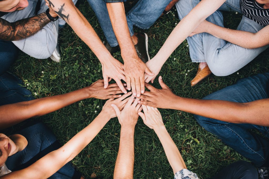 Group of diverse individuals with hands in the middle of a circle