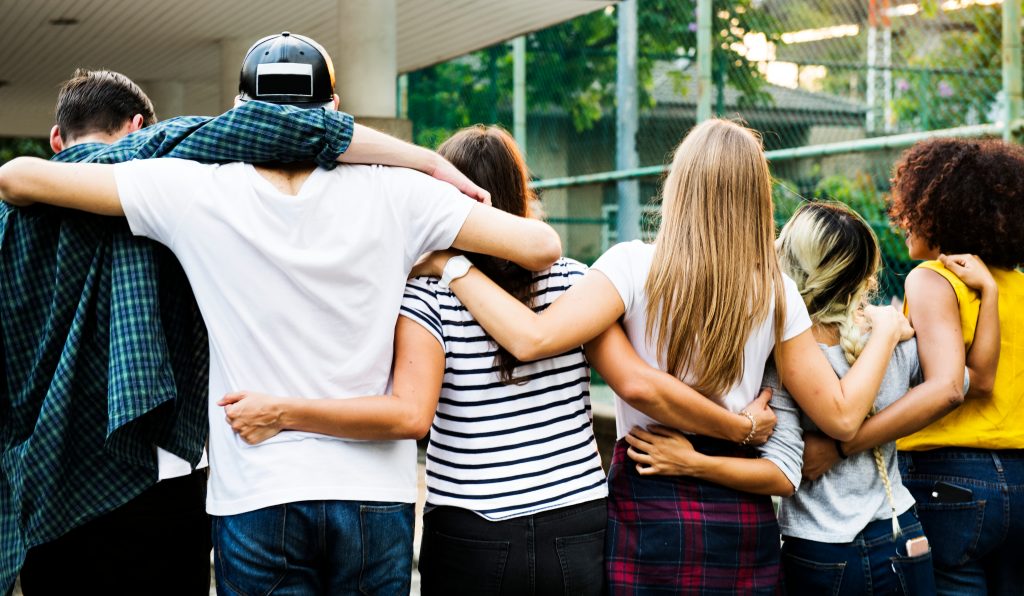 Group of young adults putting arms around each others' backs